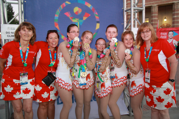 Swim team posing for the camera while kissing their medals.